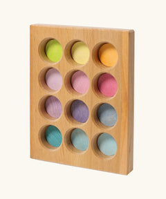 Grimms handcrafted wooden sorting board with 12 round slots in delicate pastel colours, made for sorting games