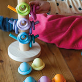 Child playing with the Grimms wooden sorting helper with rings and balls in a pastel palette