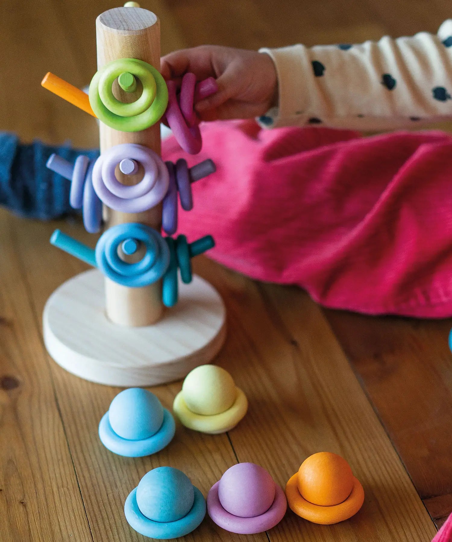 Child playing with the Grimms wooden sorting helper with rings and balls in a pastel palette