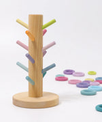 Grimms wooden sorting helper with pastel dowels and a round natural base with loose matching rings in the background