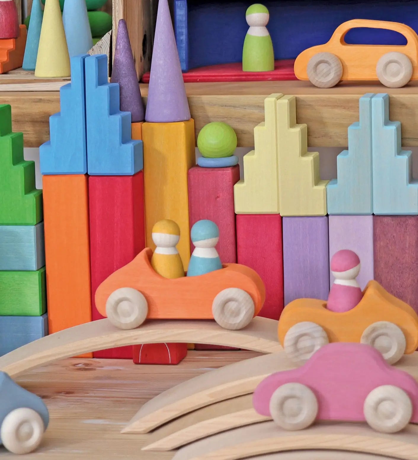 Grimm's pastel stepped roofs wooden building blocks used in a small world play set up with other Grimm's toys and cars.