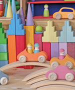 Grimm's pastel stepped roofs wooden building blocks used in a small world play set up with other Grimm's toys and cars.