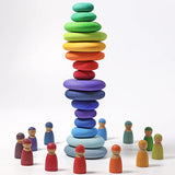 A stack made from different Grimms handcrafted wooden pebble sets with peg dolls standing in a circle