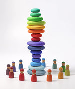 A stack made from different Grimms handcrafted wooden pebble sets with peg dolls standing in a circle