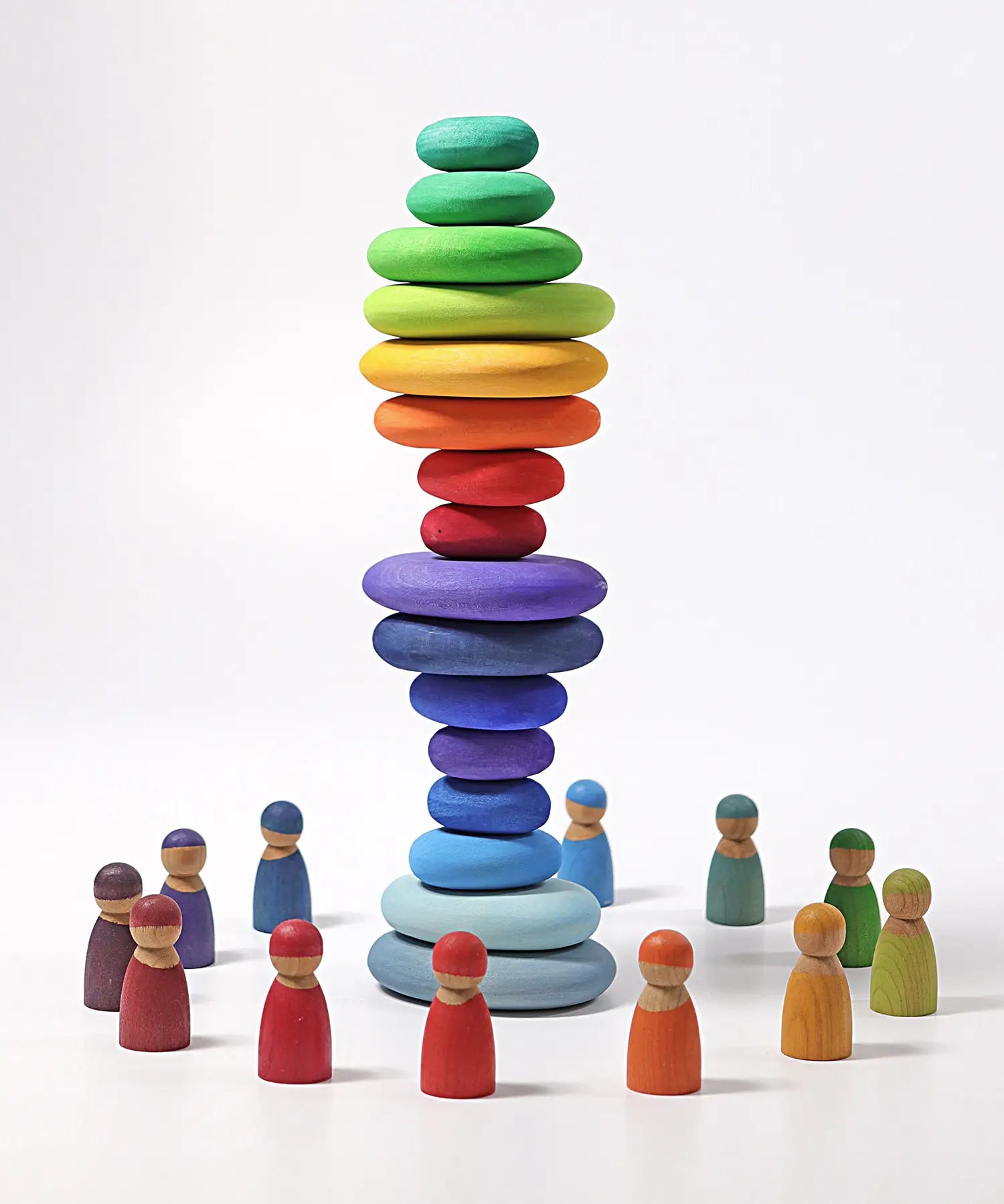 A stack made from different Grimms handcrafted wooden pebble sets with peg dolls standing in a circle