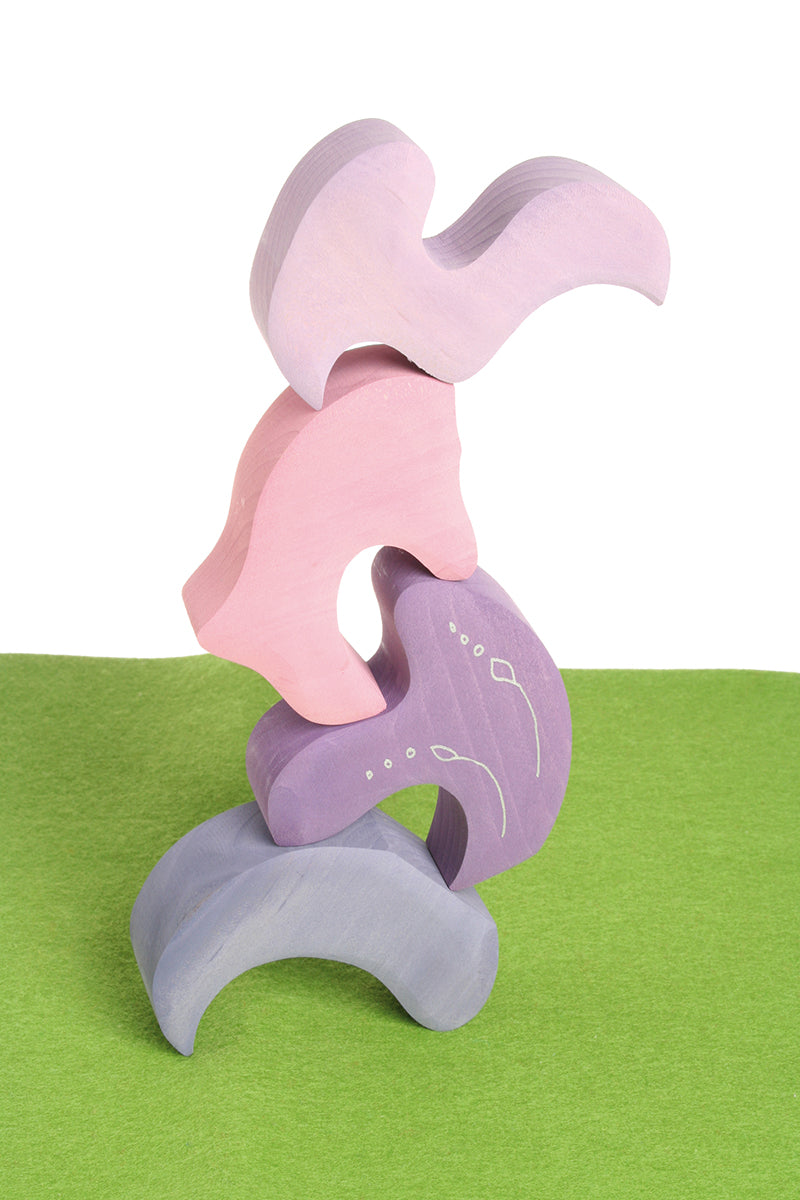 Pieces from the Grimm's casa coral wooden toy stacking puzzle stacked up. Four piece pink and lilac block puzzle.