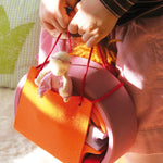 A close up of a child holding the Grimm's Pink Mobile Home wooden Toy Set.