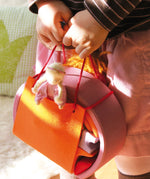 A close up of a child holding the Grimm's Pink Mobile Home wooden Toy Set.
