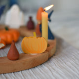 A Grimm's wooden decorative figure placed on a natural celebration ring. A lit beeswax candle and other figures can be seen in the background. The decorative figures are part of a wide range of Waldorf inspired figures and celebration rings available here at Babipur. 