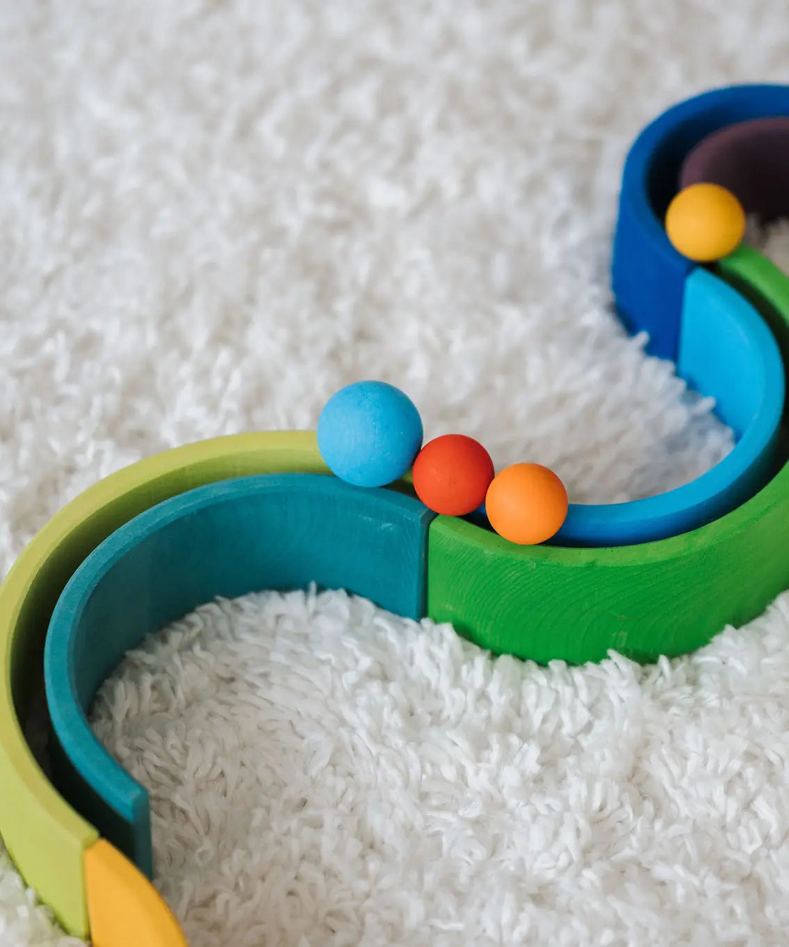 Close up of a Grimms small red and orange ball next to a large blue ball on a ball run