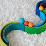 Close up of a Grimms small red and orange ball next to a large blue ball on a ball run