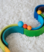 Close up of a Grimms small red and orange ball next to a large blue ball on a ball run