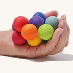 The Grimm's Rainbow Beads Grasper toy shown in an adult's hand. 