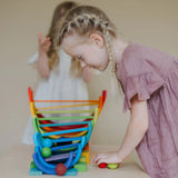 Child looking down at a ball run made from Grimms wooden rainbow pieces 
