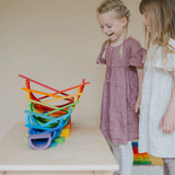 A ball running down a ball run made from Grimms rainbow building boards with children standing near