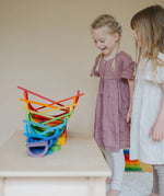 A ball running down a ball run made from Grimms rainbow building boards with children standing near