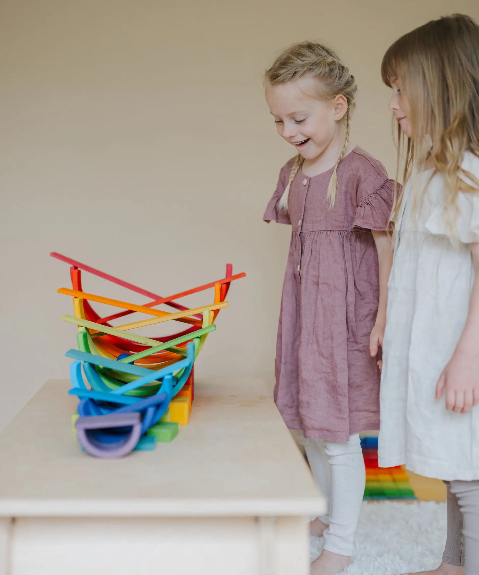 A ball running down a ball run made from Grimms rainbow building boards with children standing near