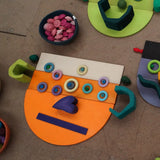 A abstract face made from Grimms wooden rainbow semi circle pieces and boards and other building blocks