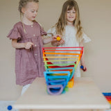 Children playing with a ball run made from Grimms wooden rainbow building boards