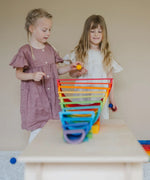 Children playing with a ball run made from Grimms wooden rainbow building boards