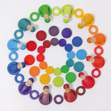 Grimms large and small wooden coins laid flat with coins and peg dolls in a rainbow palette