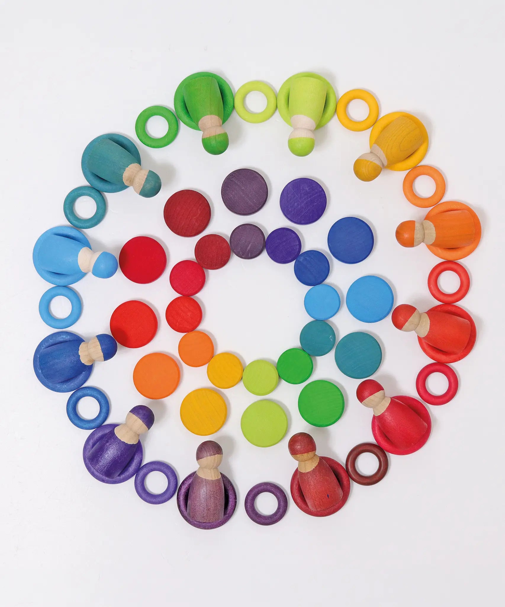 Grimms large and small wooden coins laid flat with coins and peg dolls in a rainbow palette