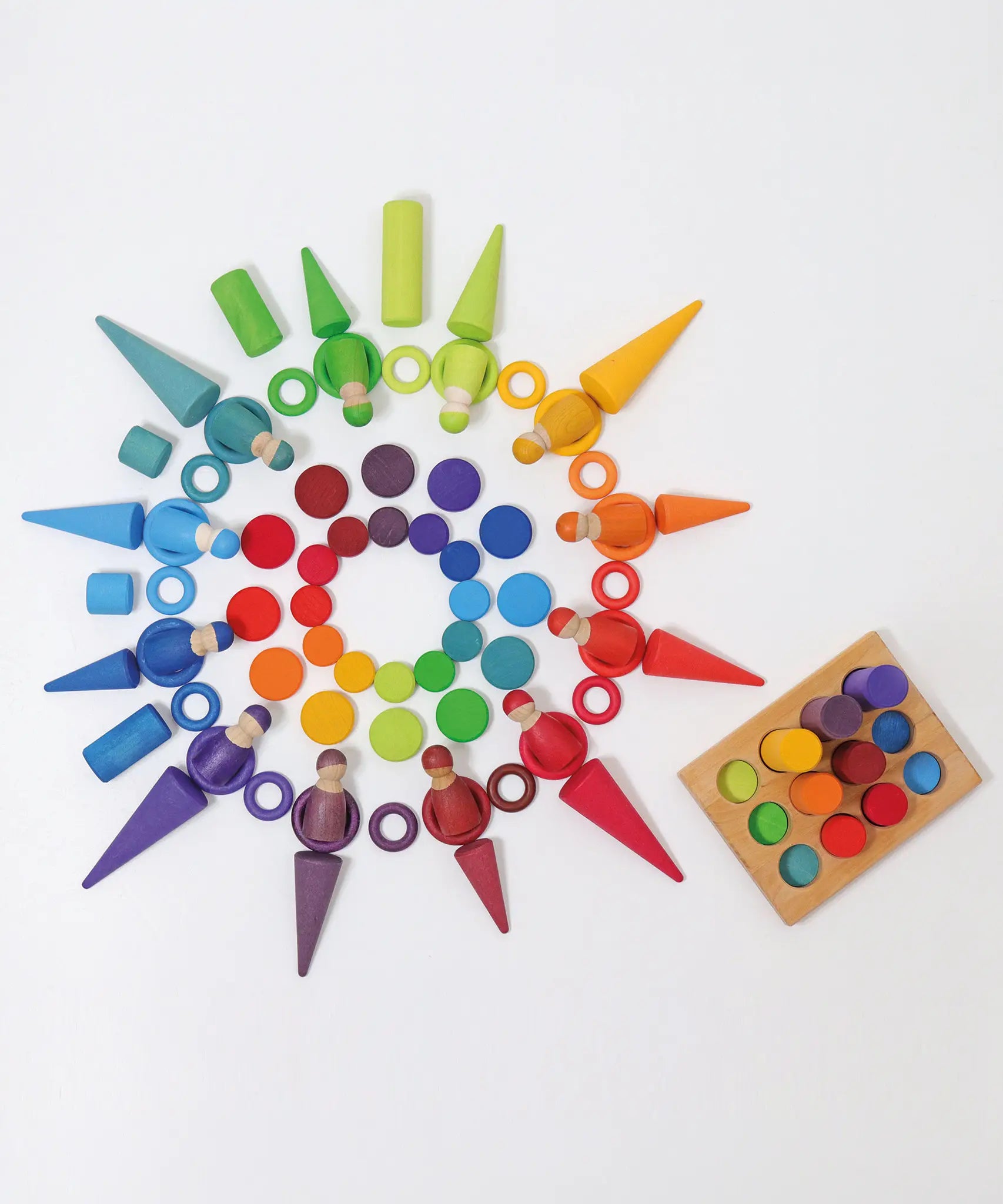 Grimms wooden coins in a pattern with other loose pieces next to a sorting board in a rainbow palette