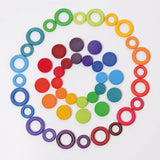 A flat lay made from Grimms wooden rings and coins in a rainbow palette 