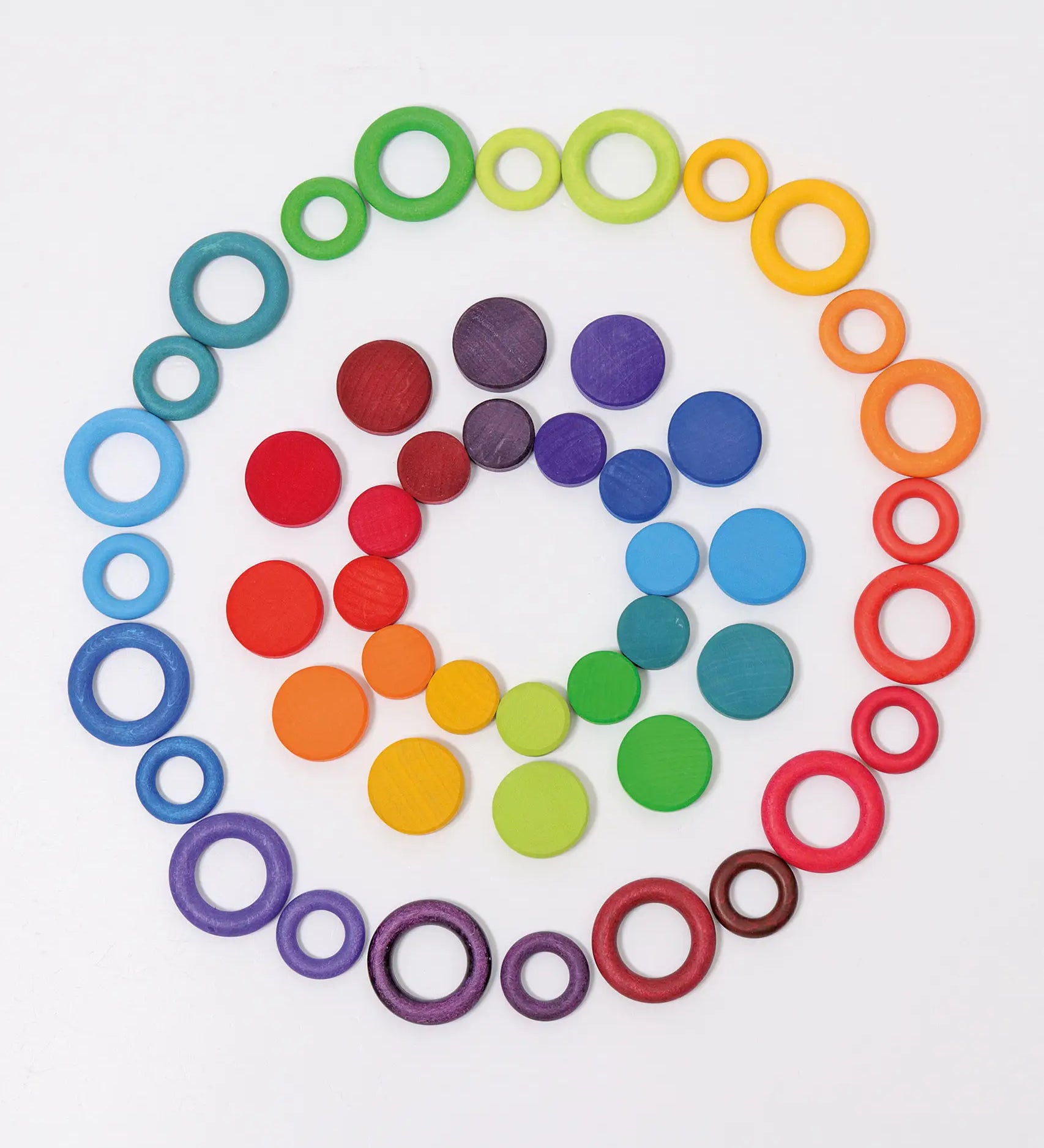 A flat lay made from Grimms wooden rings and coins in a rainbow palette 