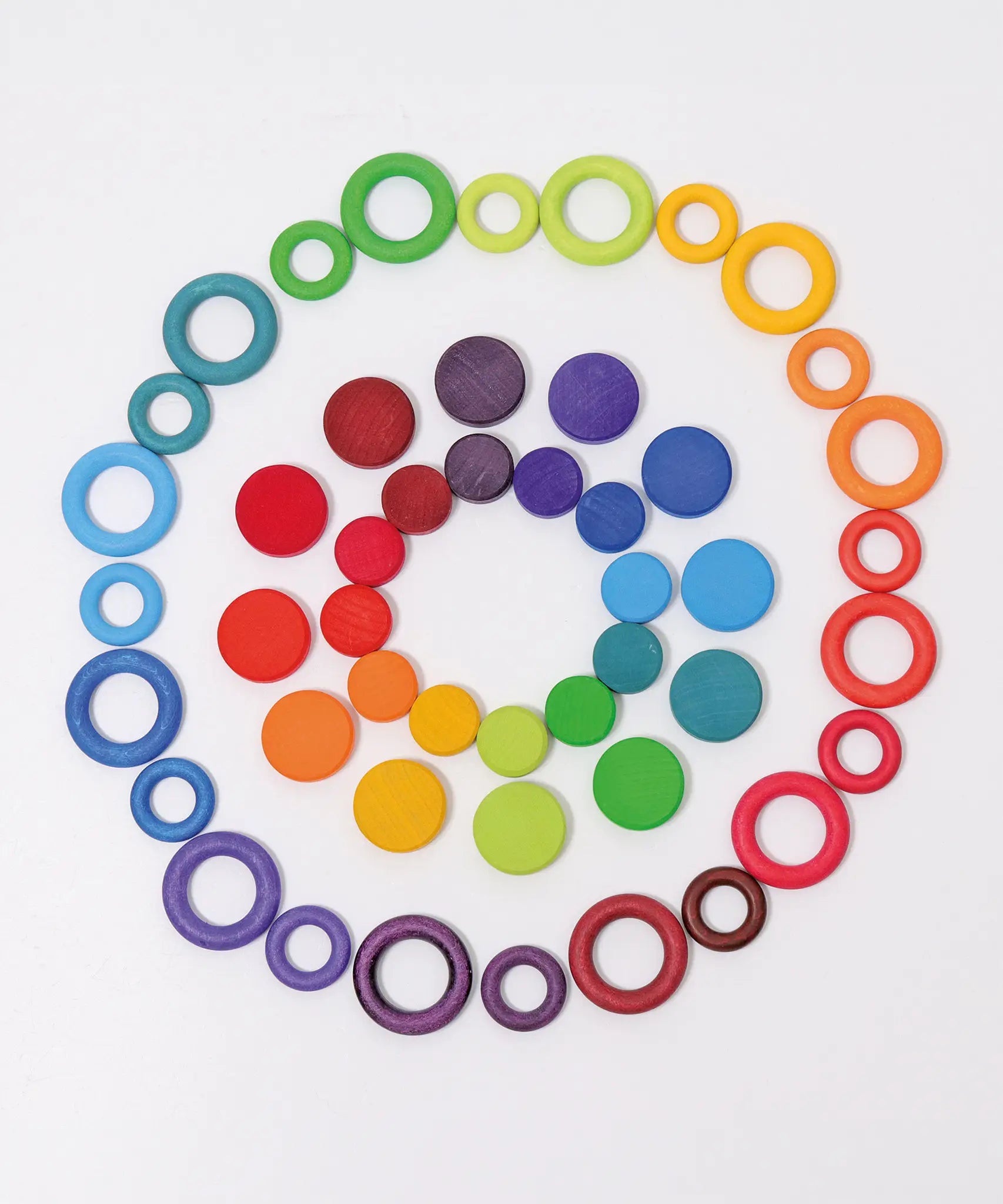 A flat lay made from Grimms wooden rings and coins in a rainbow palette 