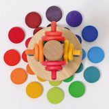Overhead view of a Grimms wooden sorting helper with rings and coins near the base