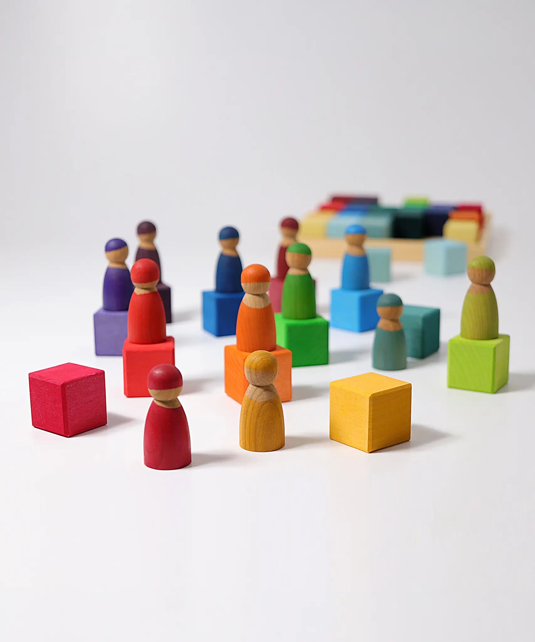 Grimms rainbow wooden cubes with Friends peg dolls on top.