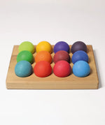 Grimms handcrafted wooden sorting board  showing rainbow coloured balls sitting on the slots
