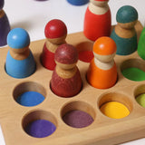 Grimms handcrafted sorting board with rainbow coloured peg dolls sitting inside the round slots 