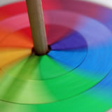 Grimms handcrafted wooden rainbow hand spinning top showing close up of the loose pieces in motion creating a blend of colours