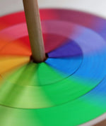 Grimms handcrafted wooden rainbow hand spinning top showing close up of the loose pieces in motion creating a blend of colours