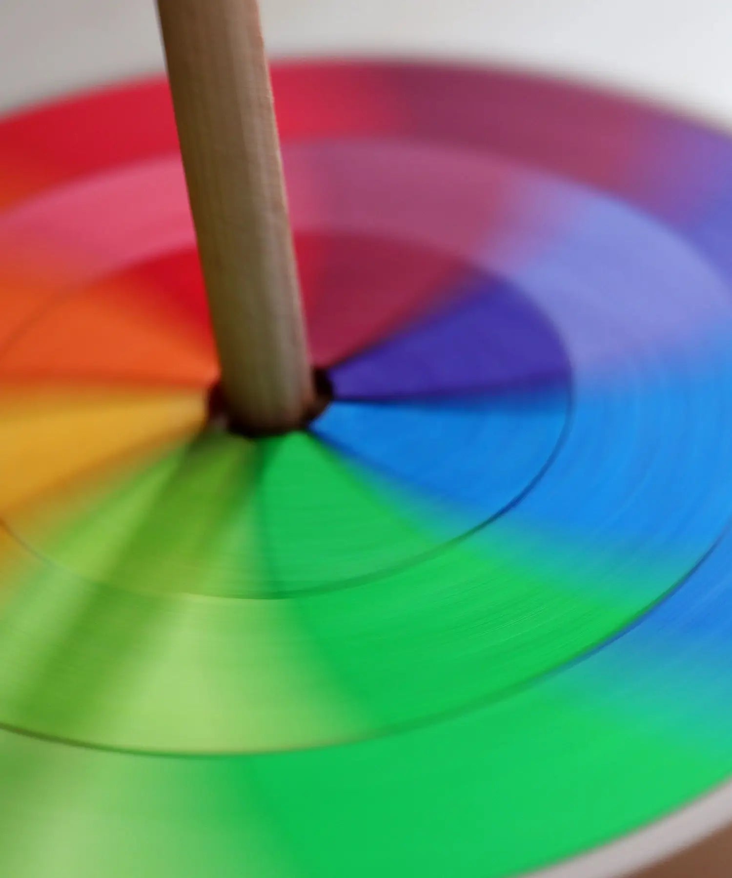Grimms handcrafted wooden rainbow hand spinning top showing close up of the loose pieces in motion creating a blend of colours