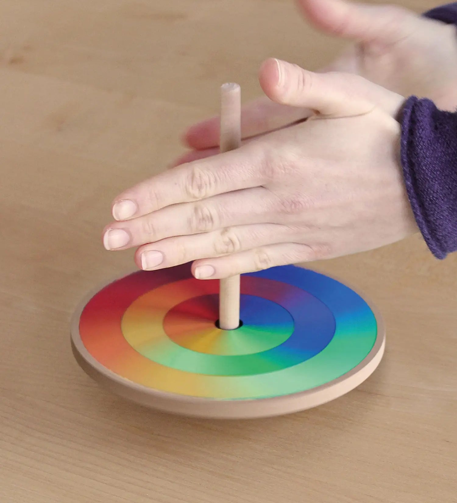 Grimms handcrafted wooden rainbow hand spinning top in action showing a blend of rainbow colours