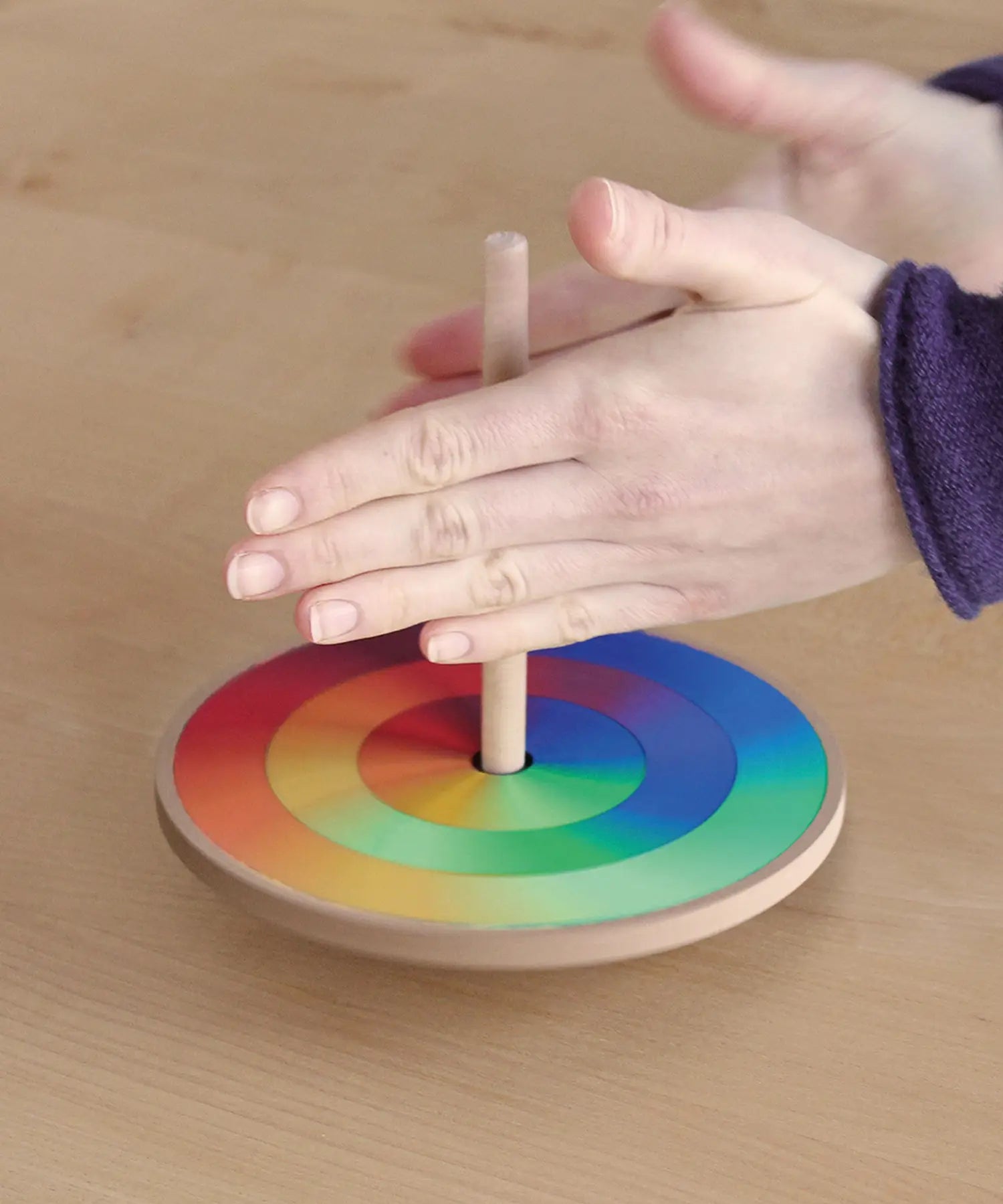 Grimms handcrafted wooden rainbow hand spinning top in action showing a blend of rainbow colours
