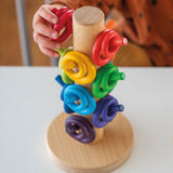 Child sorting loose Grimms wooden rings in a rainbow palette on a sorting helper. 