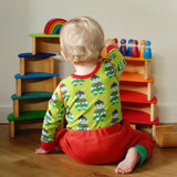 Child sitting next to a stack made from Grimms wooden rainbow semi circle and natural arch pieces