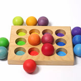 Grimms handcrafted wooden sorting board showing rainbow coloured balls on top