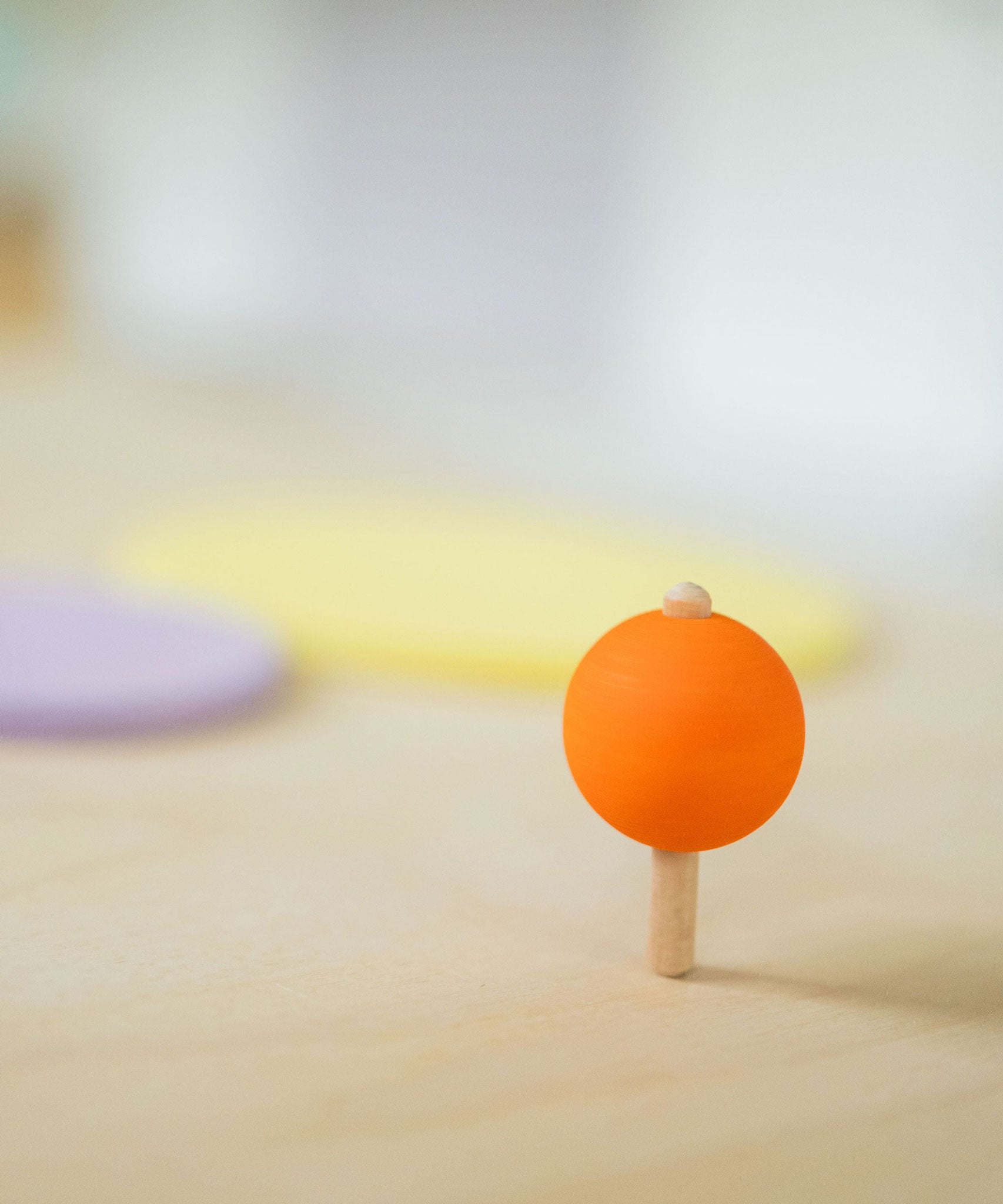 An orange coloured rainbow spinning top in motion. These Grimm's toys are part of a wide range of wooden toys available here at Babipur. 