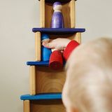 Child placing small peg dolls on a stack made using Grimms bright rainbow semi  circles