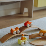Orange Grimm's wooden stacking cars toys placed on Grimm's bridge pieces. These Grimm's toys are part of a wide range of wooden toys available here at Babipur. 