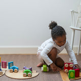 A child playing with the Grimm's wooden stacking car toys driving them over a Grimm's bridge piece. These Grimm's toys are part of a wide range of wooden toys available here at Babipur. 