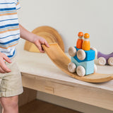 A child playing with the blue Grimm's wooden stacking car toys placing them on a Grimm's bridge piece. These Grimm's toys are part of a wide range of wooden toys available here at Babipur. 