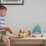A child playing with the yellow Grimm's wooden stacking car toys placing them on a Grimm's bridge piece. These Grimm's toys are part of a wide range of wooden toys available here at Babipur. 