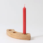 A Red 10% beeswax candle by Grimm's in a brass holder and celebration ring. White background