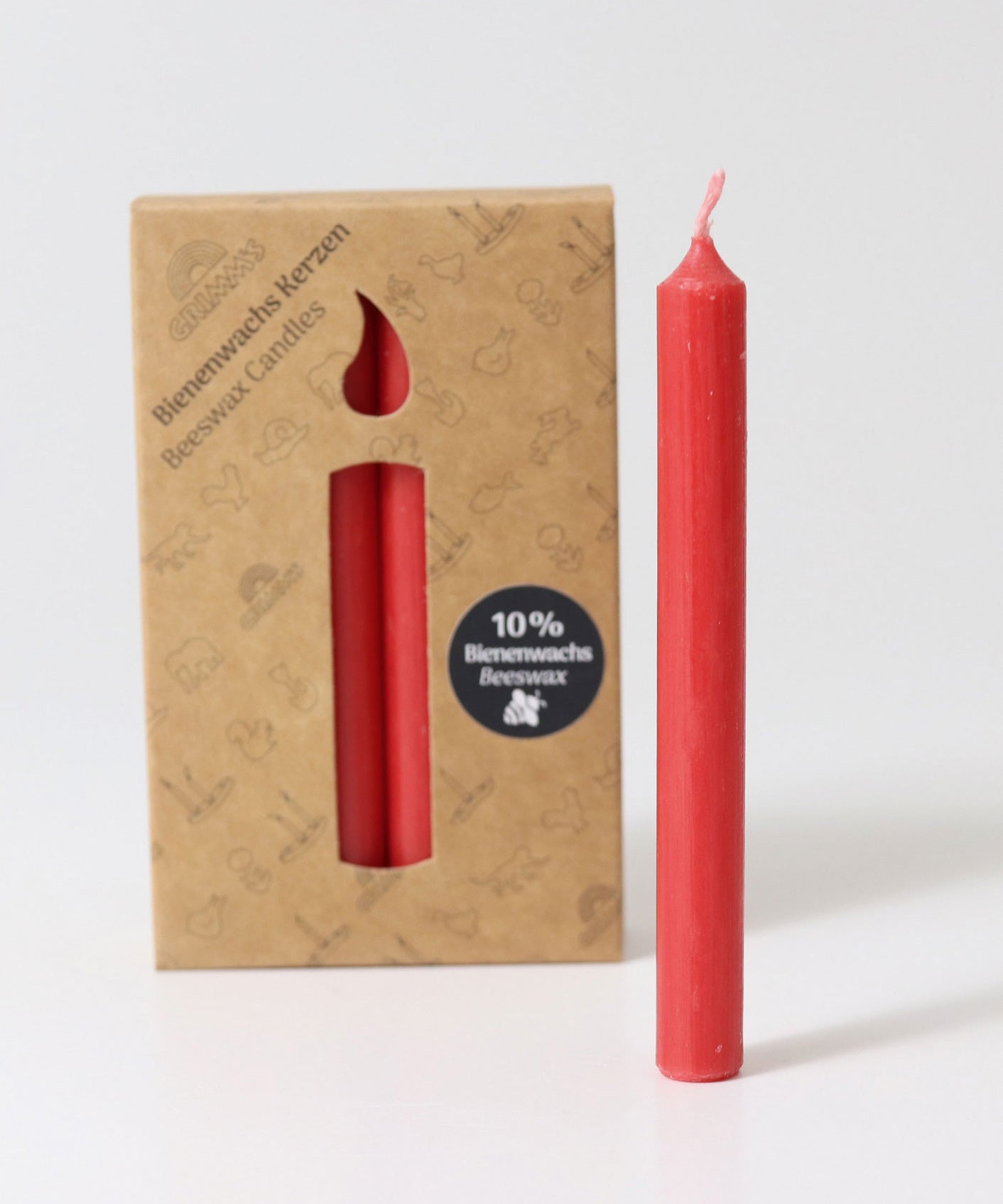 A pack of 12 Red 10% beeswax candles by Grimm's with one red candles placed in front of the box.